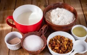 Paruoškite ingredientus. Kefyrą šiek tiek pakaitinkite puode ant silpnos ugnies. Razinas nuplaukite šaltame vandenyje.