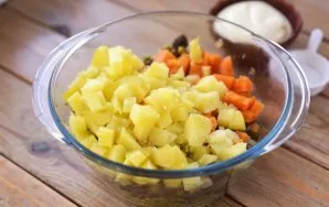 Į dubenį su likusiais ingredientais sudėkite pjaustytus kiaušinius, bulves ir morkas.