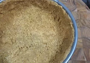 Gautą masę dėkite į kepimo indą taip, kad ji atitiktų dugno ir šonų formą. Paspauskite, kad jis nesuirtų.