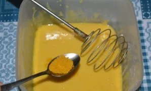 Į kiaušinių mišinį įberkite indiško kario prieskonių ir vėl maišykite, kol ištirps visi sausieji ingredientai.