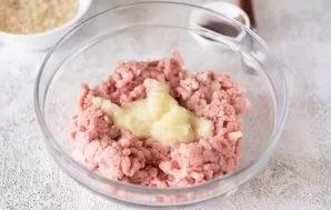 Maltą mėsą sudėkite į didelį dubenį ir smulkia tarka sutarkuokite vieną svogūną.