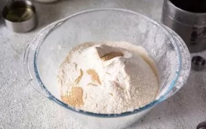 Į didelį dubenį persijokite miltus ir suberkite momentines mieles.