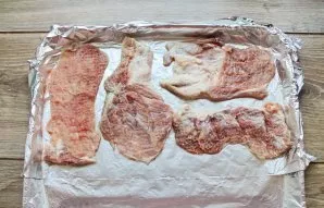 Kiaulieną supjaustykite porcijomis, išmuškite, pasūdykite ir pipiriuokite. Kepimo skardą uždenkite folija ir sudėkite sudėkite kiaulienos...