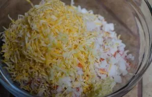 Sūrį sutarkuokite vidutine tarka. Sumaišykite su smulkintais ingredientais ir pagardinkite majonezu.