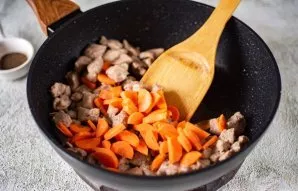 Į mėsą sudėkite morkas ir viską kartu kepkite ant vidutinės ugnies dar apie 5 minutes.