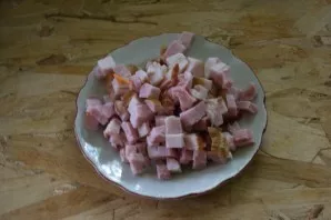 Rūkytus lašinius arba šoninę supjaustykite kubeliais.