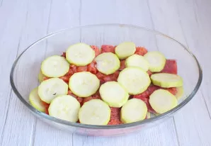 Paimkite kepimo indą. Išdėliokite 1/2 susmulkintas cukinijas.