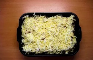 Sūrį sutarkuokite ir pabarstykite ant viršaus. Uždenkite dangčiu arba folijos lakštu. Skardą pašaukite į įkaitintą orkaitę ir kepkite vid...